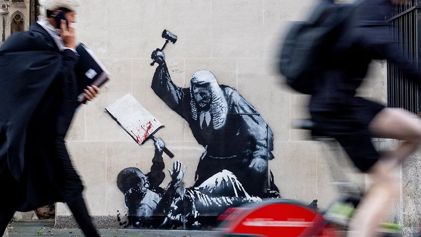 Banksy sacude Londres con mural de juez golpeando manifestante en Tribunales Reales.